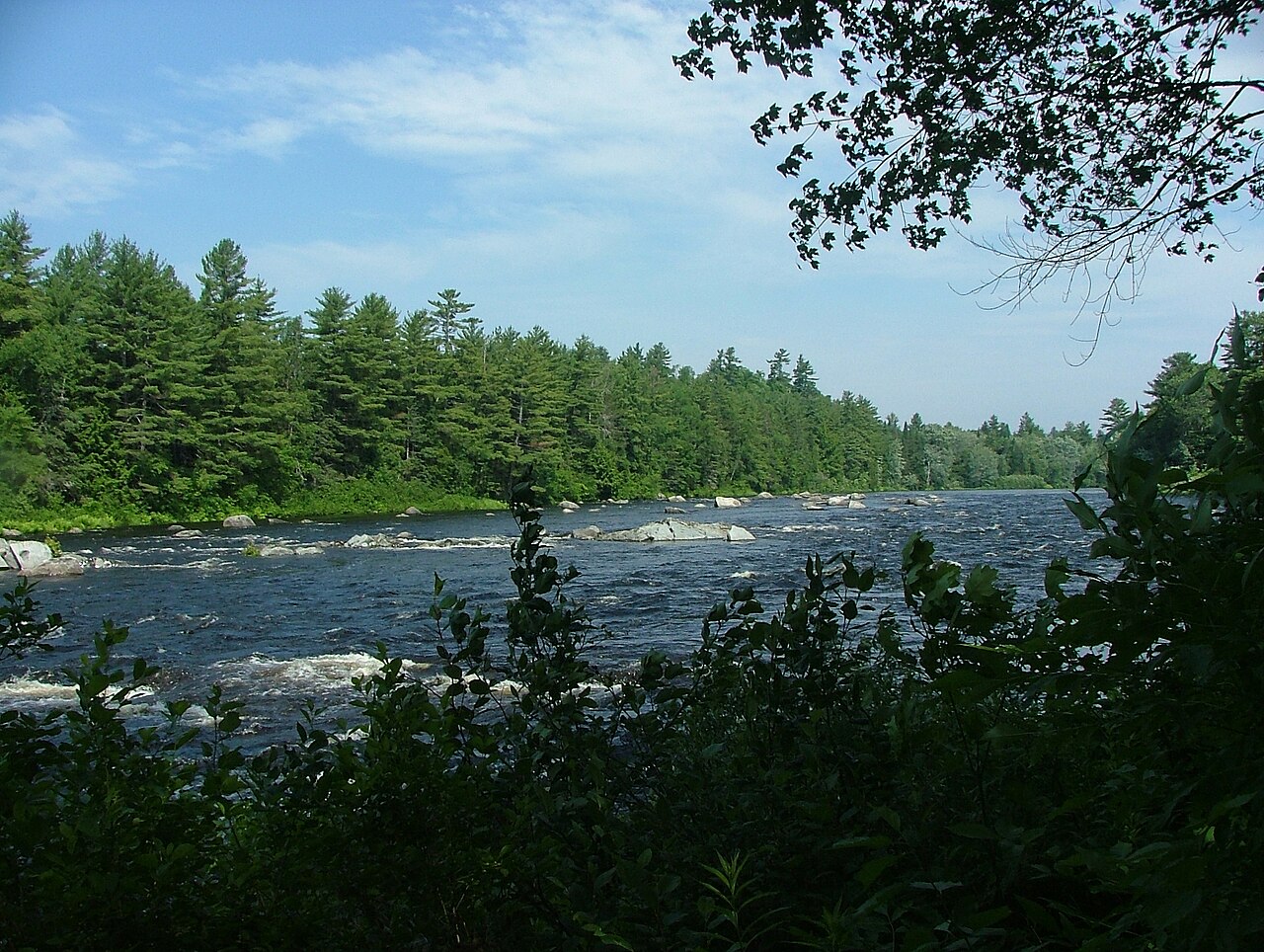 Rapids tumbling around boulders on a river in the Katahdin Woods and Waters region of Maine