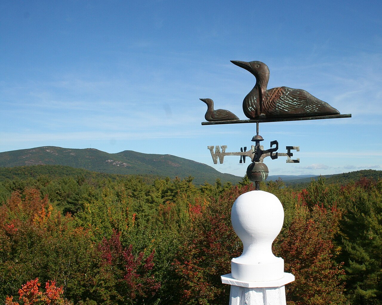 Pleasant Mountain rising over the forested western Maine Lakes Region under a blue sky