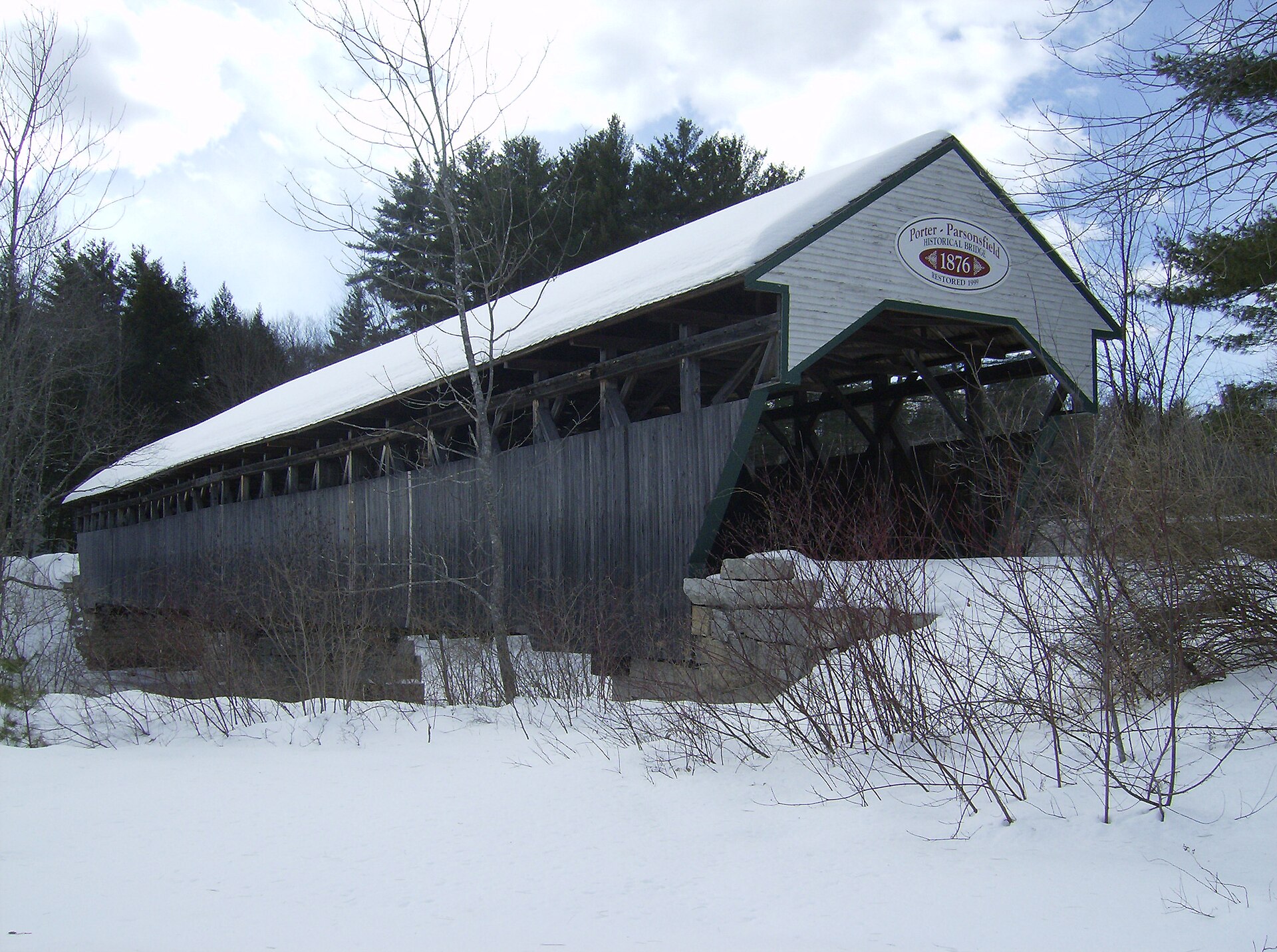 The snow-covered Porter-Parsonsfield covered bridge over the Ossipee River at Kezar Falls, Maine