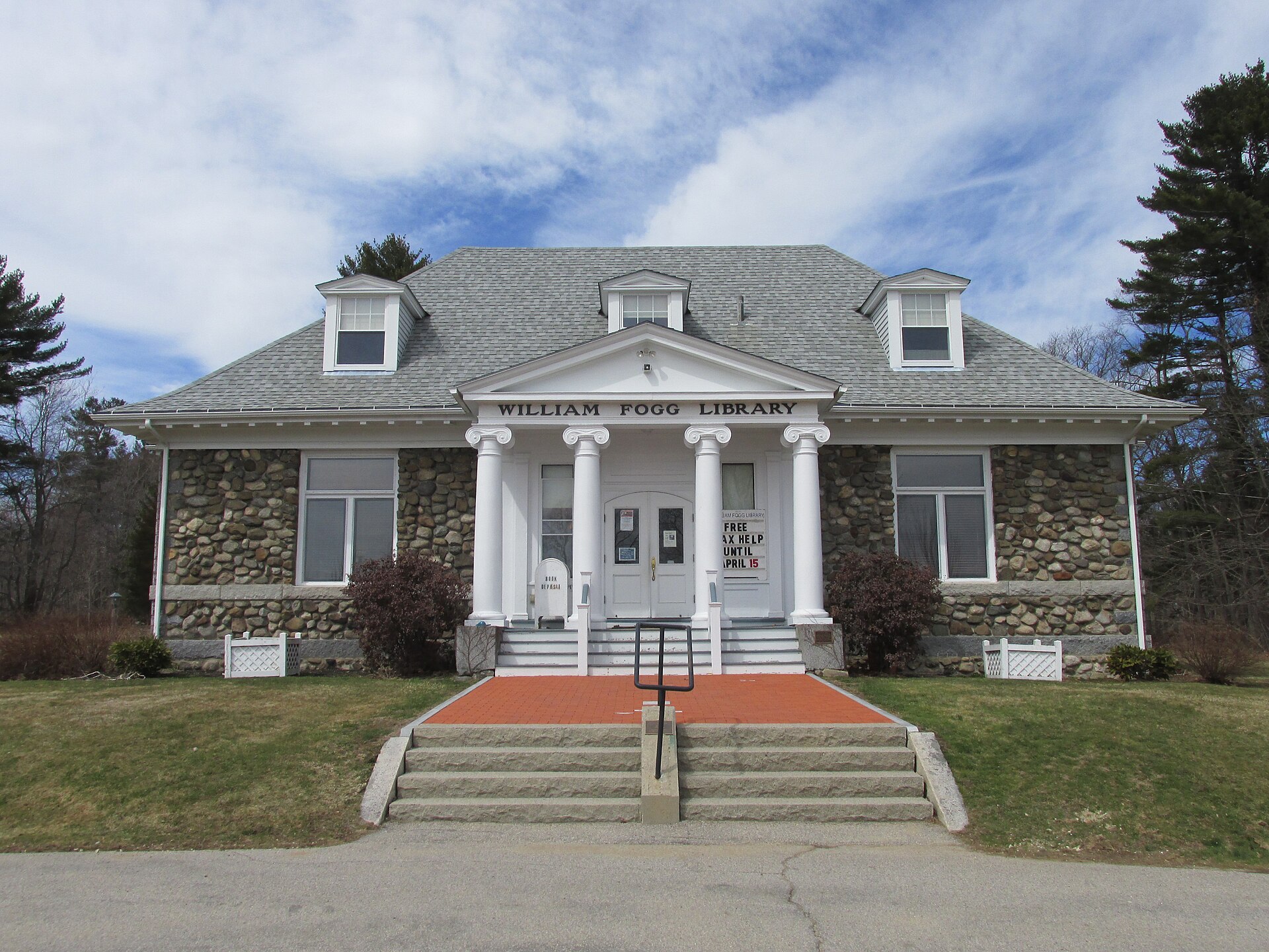 The stone William Fogg Library building with white columns in Eliot, Maine